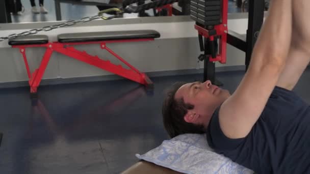 training in a fitness club. Strong muscular athlete in a t-shirt and shorts performs exercises while Pullover on lower block lying on a horizontal bench. gym workout. Sport lifestyle concept. - Záběry, video