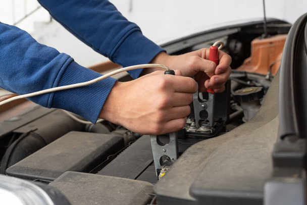 Closeup of the hands of a mechanic using jumper cables to start a car - Fotografie, Obrázek