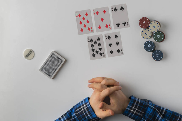 a top view of dealer holding chips and cards in the poker game on white table - Fotoğraf, Görsel