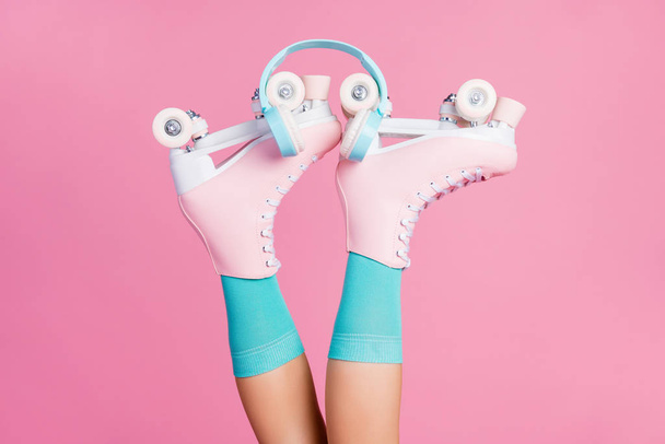 Cropped view of one person nice attractive fashionable lovely legs wearing blue sock skates ear phones new radio hit lifestyle isolated over pink pastel color background - 写真・画像