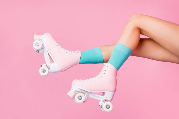 Cropped profile side view of nice attractive lovely feminine long legs wearing blue socks skates skating posing having fun in air isolated over pink pastel color background - Foto, Imagem
