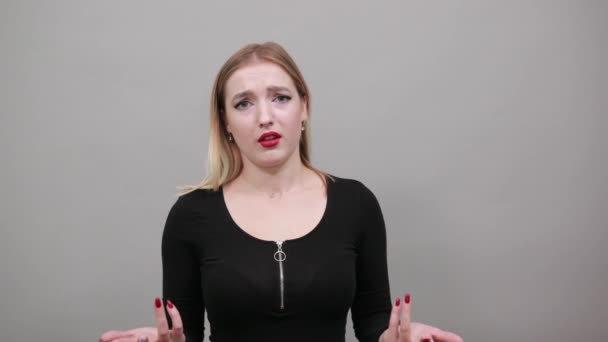 Fiatal szőke lány fekete dzsekiben zavarodott nő széttárja a kezét - Felvétel, videó