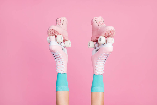 Cropped view of nice attractive legs wearing blue comfortable socks skate rollers holding new brandy shoes isolated over pink pastel color background - Photo, Image