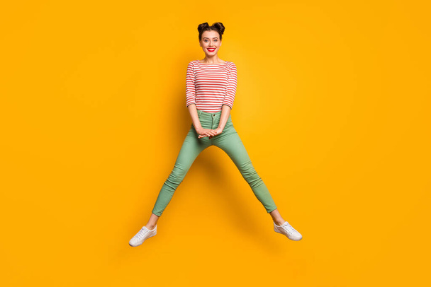 Full length photo of attractive pretty lady jumping high up traveler abroad spread legs wear red white pullover shirt green pants footwear isolated bright yellow background - Photo, Image