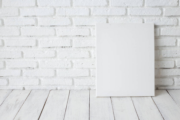Empty white canvas frame on a wooden table - Foto, imagen