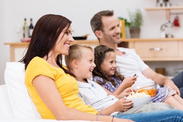 Onnellinen nuori perhe katsomassa televisiota
 - Valokuva, kuva
