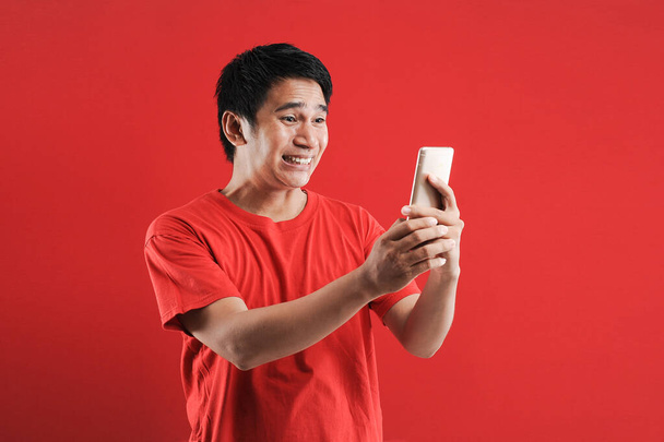Щасливий азіатський чоловік читає новий текст на мобільному - Фото, зображення