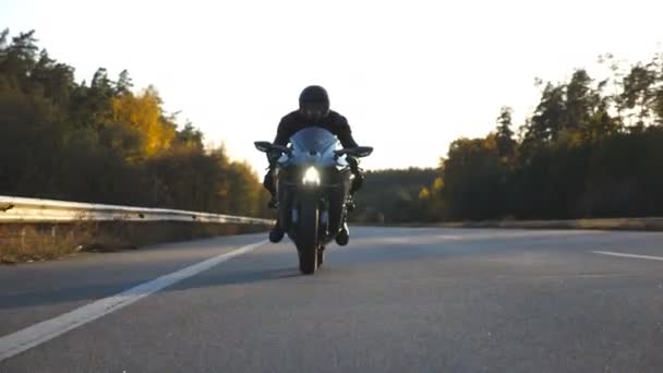 Motorcyclist racing his motorcycle on country road. Young man in helmet riding fast on modern sport motorbike at highway. Guy driving bike during trip. Concept of adventure. Front view Close up - Footage, Video