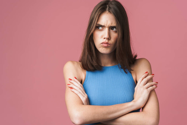 Image of angry brunette woman frowning and standing with arms cr - Foto, afbeelding