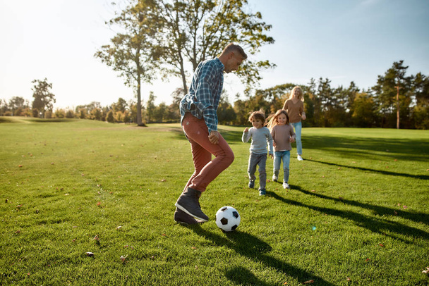 A nurturing and creative world. Happy family playing with a ball on meadow - Foto, imagen