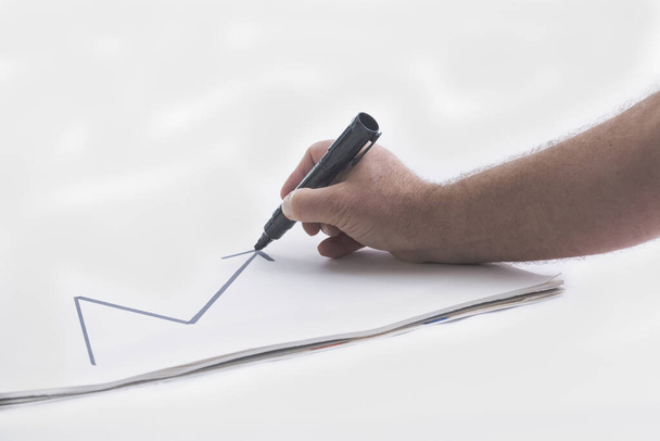 Erkek el kağıt üzerinde yukarı doğru bir çizgi çiziyor. - Fotoğraf, Görsel
