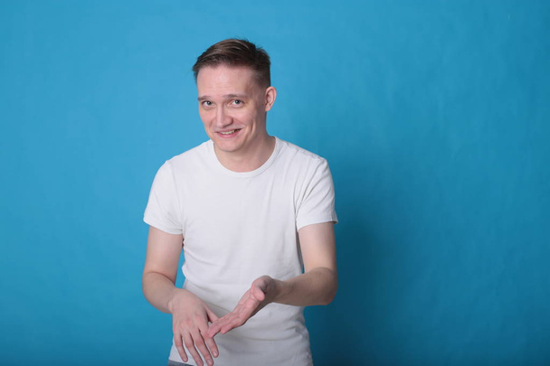 modern portré hangulatos elegáns fiatal férfi fehér pólóban fényes kék háttér - Fotó, kép