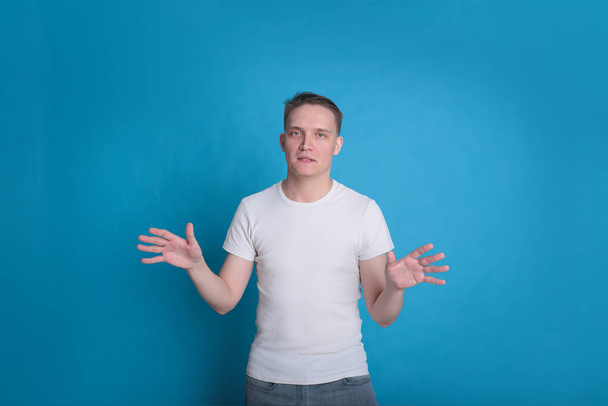 современный портрет эмоциональный стильный стильный молодой человек в белой футболке на ярко-синем фоне
 - Фото, изображение