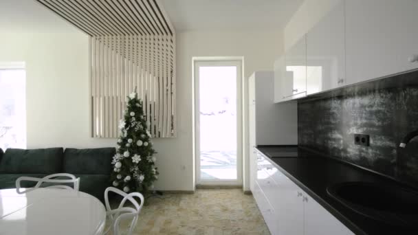 Wnętrze nowoczesnej przestronnej kuchni z białymi ścianami, dekoracyjnymi elementami drewnianymi, nowoczesnymi meblami i dużą miękką kanapą. - Materiał filmowy, wideo
