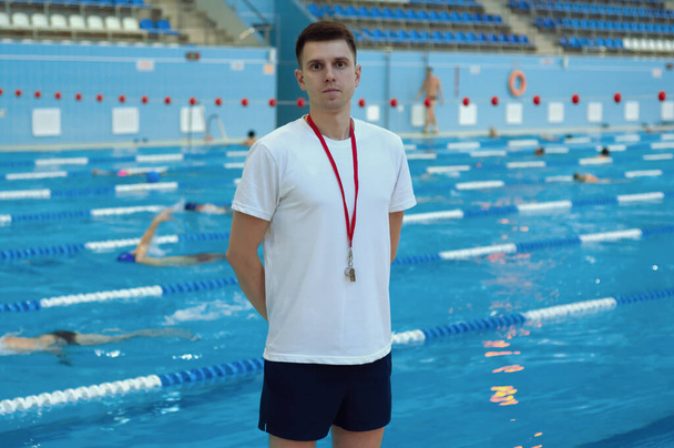 Handsome trainer in white T-shirt standing at the swimming pool. - Foto, Imagem