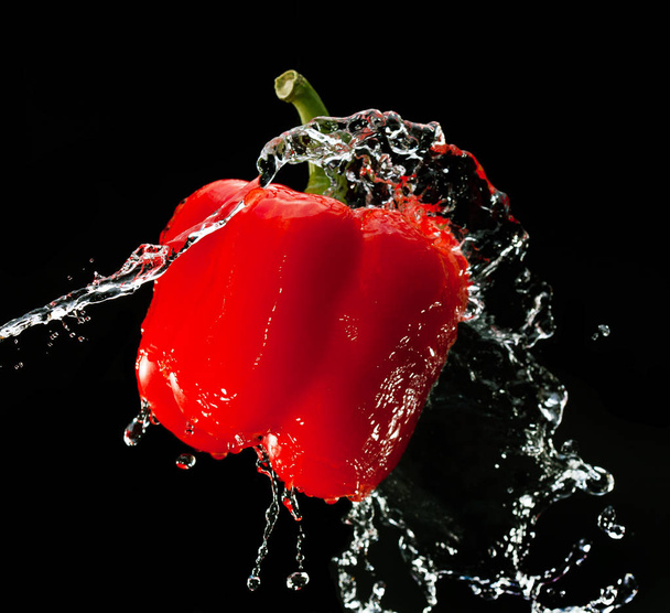 pimiento rojo fresco es golpeado por un chorro de agua
 - Foto, Imagen