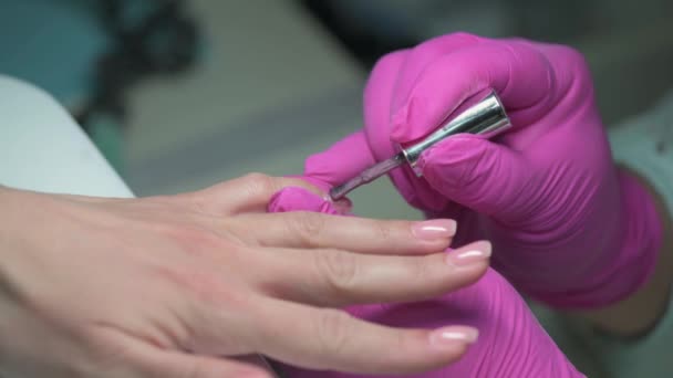 Closeup of manicure beautician covering clients nails with glitter nail polish - Video