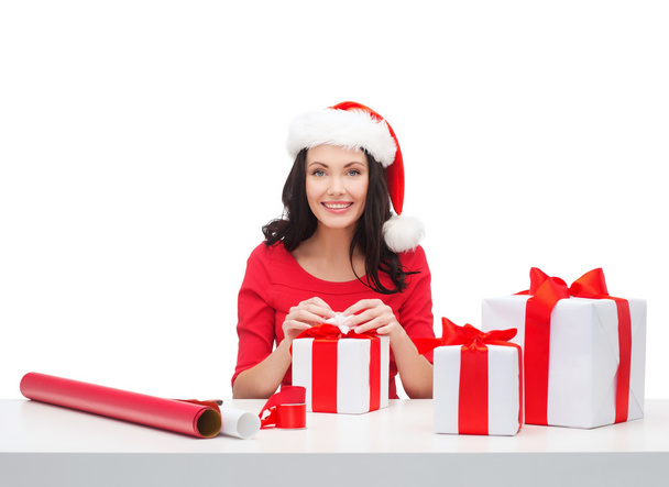 vrouw in helper kerstmuts met vele geschenkdozen - Foto, afbeelding