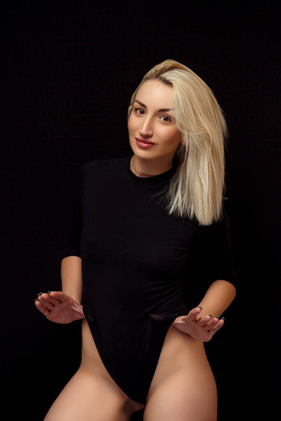 young Caucasian beautiful blonde woman posing in a black bodysuit . - Fotografie, Obrázek