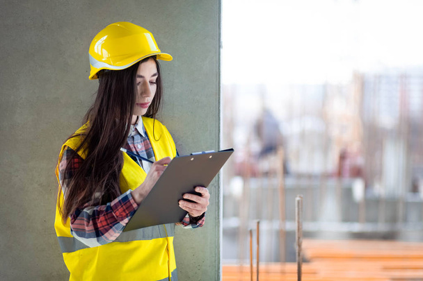 Trabajadora de la construcción con un portapapeles en la mano inspecciona el proceso de construcción
 - Foto, Imagen