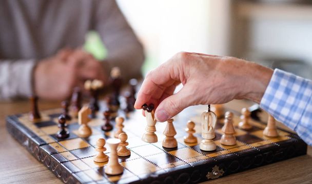 Midsection of senior men friends at home, playing chess. - 写真・画像