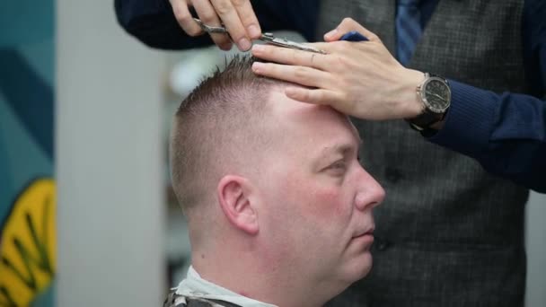 Mens haircut in Barbershop. Close-up of master clipping a man with blond hair with scissors - Video