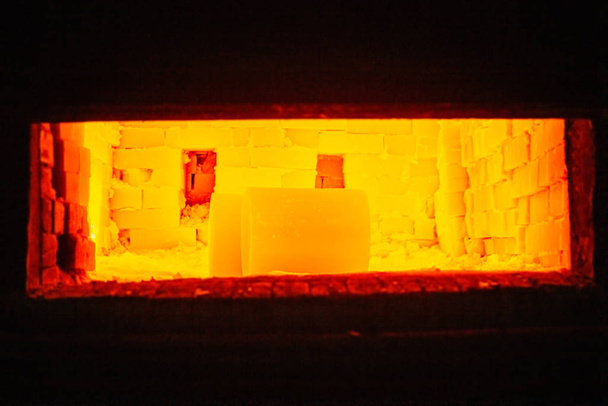Пара важких гарячих жовтих блискучих циліндричних заготовок, що нагріваються всередині газової печі
 - Фото, зображення