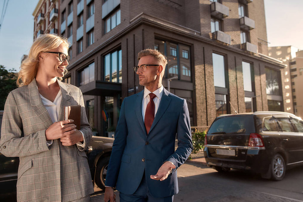 Happy to be your partner. Two cheerful business people in classic wear talking about new project and smiling while walking outdoors - Valokuva, kuva