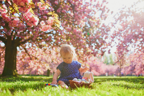 Cute one year old girl sitting on the grass and eating strawberries - Valokuva, kuva
