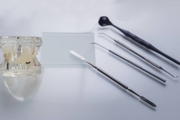 вид сверху, медицинские стоматологические инструменты, на стерильном столе стоматолога. Рядом с манекеном человеческих челюстей и зубов. Медицинский флатлей
 - Фото, изображение