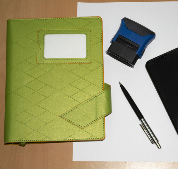 зеленый Дневник с ручкой, штампом и смартфоном на дереве
 - Фото, изображение