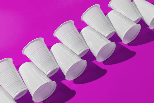 abstract pattern of plastic cups on color surface with harsh trendy shadows - Foto, afbeelding