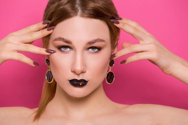 A beautiful young girl of European appearance with beautiful make-up on a pink background. Beauty Shooting - Photo, Image