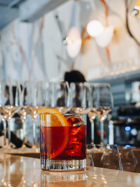 Red alcohol cocktail in glass with orange and ice - Zdjęcie, obraz
