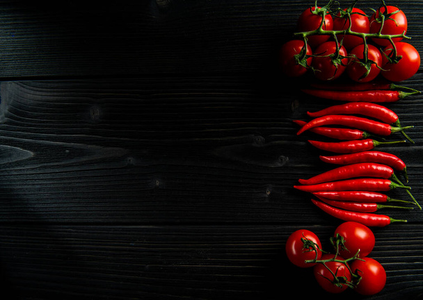 cherry rajčata a chilli papričky na černém dřevěném pozadí - Fotografie, Obrázek