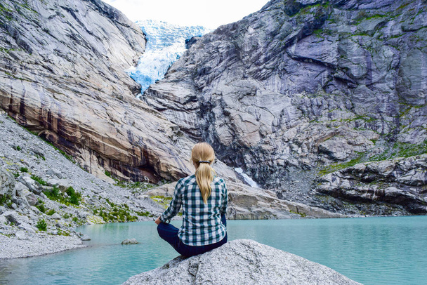 De jonge vrouw bij de Briksdalsbren gletsjer. Noorwegen. - Foto, afbeelding