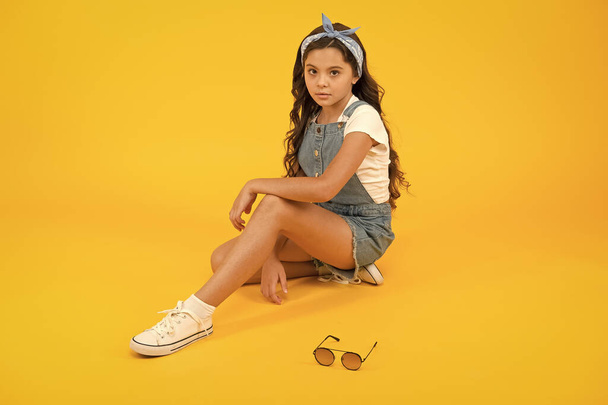 Casual but amazing look. Adorable girl with fashion look on yellow background. Cute little child have glamour look of long curly hairstyle. Vogue look of small fashion model - Foto, Imagen