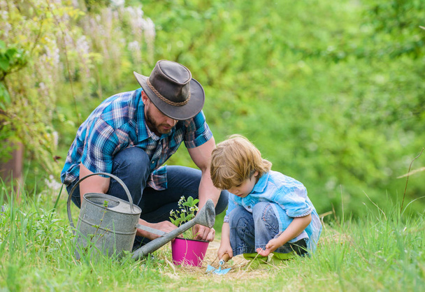 Little helper in garden. Make planet greener. Growing plants. Take care of plants. Day of earth. Boy and father in nature. Gardening tools. Planting flowers. Dad teaching little son care plants - 写真・画像