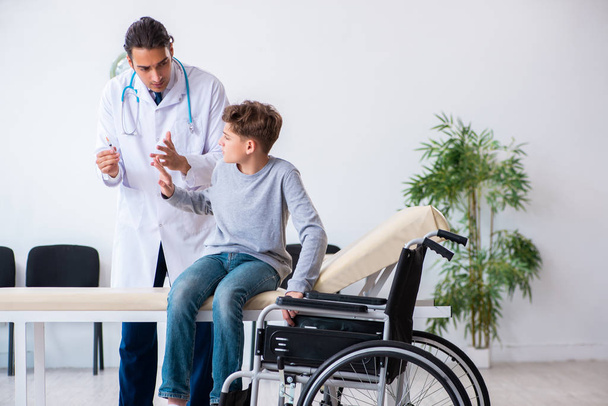 Молодий чоловік лікар педіатр і хлопчик в інвалідному кріслі
 - Фото, зображення
