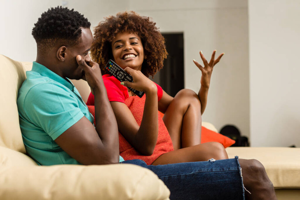 Black African American couple watching tv in the living room - Foto, imagen