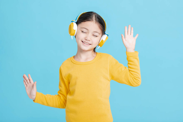 Happy little girl   listens to music in headphones - Foto, Imagen