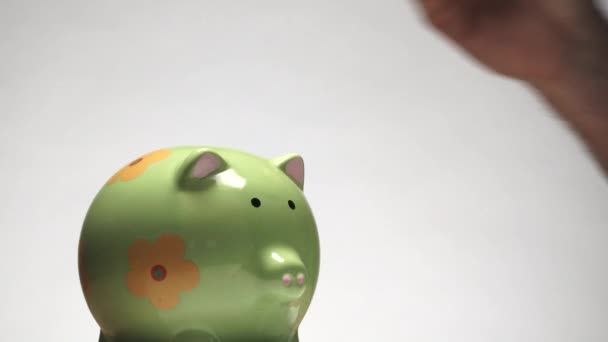 In studio, person adds coins to a piggy bank for future spending, close up. - Footage, Video