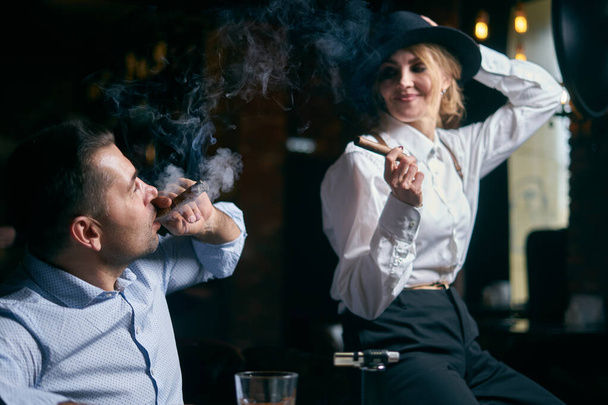 Erkek-gangster ve güzel son sınıf öğrencisi bir barda puro içiyor. - Fotoğraf, Görsel