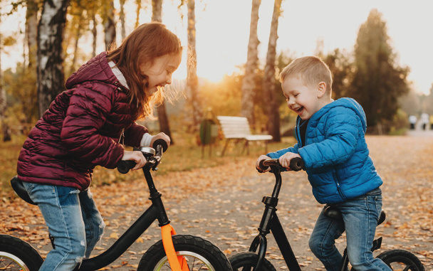 Kaksi kaveria, joilla on iltakävely puistossa polkupyöriensä kanssa, leikkivät onnellisina välittämättä mistään.
 - Valokuva, kuva