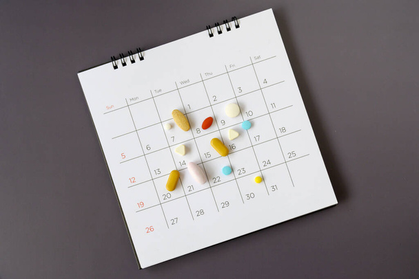 Pastillas sobre un fondo de calendario. concepto Asistencia sanitaria
 - Foto, imagen