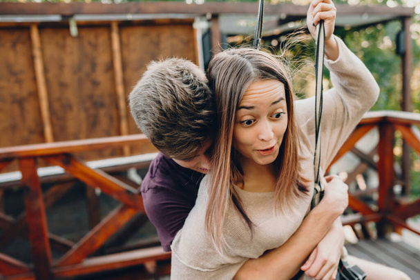 A careful caucasian boy embracing his girlfriend while she feels scared of a ropeway trip - Фото, зображення