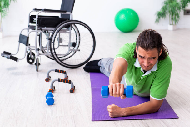 Young man in wheel-chair doing exercises indoors - Photo, Image