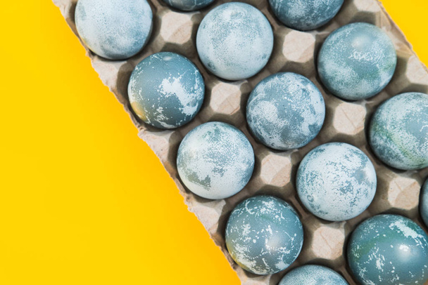 Blue textured colored Easter eggs on a bright yellow holiday background backdrop. Spring holiday concept. Copyspace. Flat lay. Top view. - Foto, Imagem