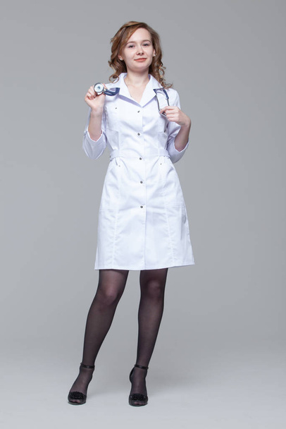 Full-length portrait of female doctor with stethoscope standing and looking at camera - Foto, afbeelding