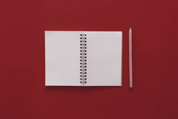 Notatnik i ołówek na czerwonym tle tekstury. - Zdjęcie, obraz